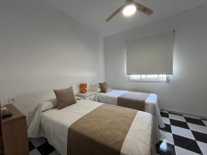 a hotel room with two beds and a window at Isabella Chipiona in Chipiona