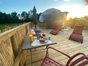 a table with a plate of food on a deck at le dôme avec bain nordique in Amfroipret