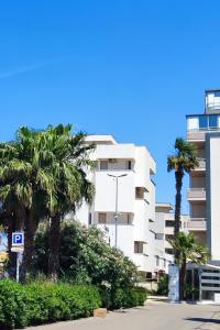 a white building with palm trees in front of it at luxury studio in Gallipoli