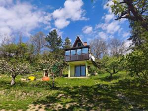 a small yellow house on a hill with trees at Iza sedam gora in Rakovac