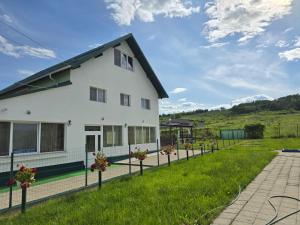 a white house with a green field in the background at Casa Diadeea Motru in Motru