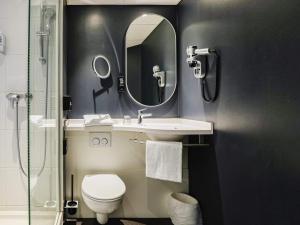 a bathroom with a sink and a toilet and a mirror at Ibis Luxembourg Airport in Luxembourg