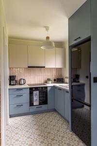 a kitchen with white cabinets and an open door at Domki Śluza 23 in Dywan