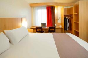 a bedroom with a white bed and a desk with a computer at ibis Hotel Brussels Airport in Diegem +101 photos