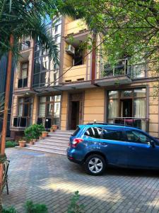 a blue car parked in front of a building at Nelly Hotel in Batumi