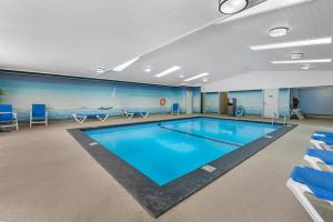 a swimming pool in a room with blue chairs and chairs at SureStay Plus Hotel by Best Western Salmon Arm in Salmon Arm