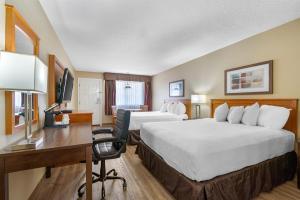 a hotel room with two beds and a desk at SureStay Plus Hotel by Best Western Salmon Arm in Salmon Arm