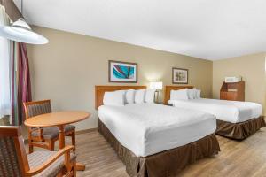 a hotel room with two beds and a table at SureStay Plus Hotel by Best Western Salmon Arm in Salmon Arm +27 photos