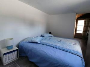 a bedroom with a bed with blue sheets and a window at L'Olivier des Dunes in Saint-Georges-dʼOléron