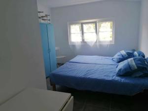 a bedroom with a bed with blue sheets and two windows at L'Olivier des Dunes in Saint-Georges-dʼOléron