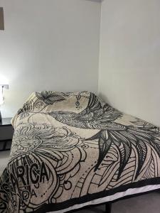 a bed with a black and white comforter at Hummingbird Haven in Uvita