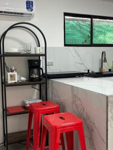 a kitchen with two red stools in front of a counter at Hummingbird Haven in Uvita