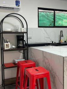 a kitchen with two red stools in front of a counter at Hummingbird Haven in Uvita +12 photos