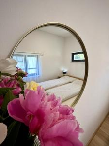 a mirror in a room with a bed and flowers at JUNÁK MINI ubytování v soukromí in Vranov nad Dyjí