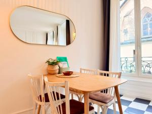 a dining room table with chairs and a mirror at Le Chamily in Besançon