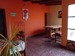 a room with an orange wall and a table at HOSPEDAJE LA CASONA DE CACHI in Cachí +29 photos