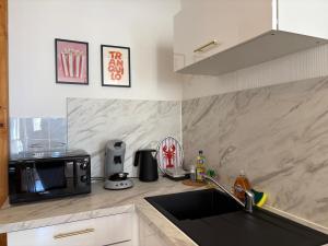 a kitchen with a sink and a microwave at L'Orelia - confortable T2 hyper centre in Montélimar +11 photos