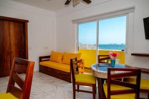 a living room with a yellow couch and a table at Happy Beach - Playa Feliz in Ixtapa-Zihuatanejo International