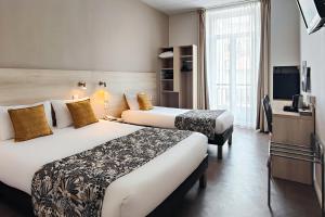 a hotel room with two beds and a television at Hôtel Helvétique in Nice