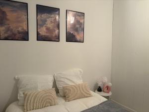 a white bed with four pictures on the wall at L'Orelia - confortable T2 hyper centre in Montélimar