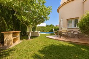 a backyard with a table and a tree at Villa Oliva Nova - Private Pool in Casas Devesa