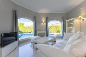 a living room with white furniture and a tv at Villa Oliva Nova - Private Pool in Casas Devesa
