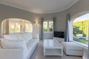 a living room with a white couch and a tv at Villa Oliva Nova - Private Pool in Casas Devesa +12 photos