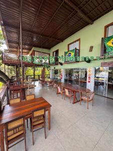 a restaurant with wooden tables and chairs and windows at Pousada Recanto das Chalanas in Corumbá