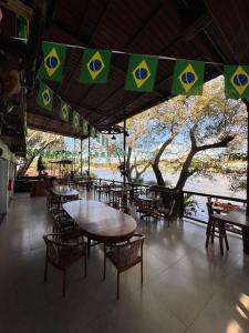 a restaurant with tables and chairs and a view of a river at Pousada Recanto das Chalanas in Corumbá