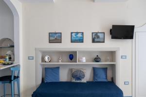 a bedroom with a blue bed with a tv above it at Libeccio - flat with terrace and sea view, perfect for up to 3 guests in Maiori