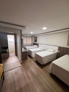 a hotel room with three beds and a piano at Pousada Recanto das Chalanas in Corumbá