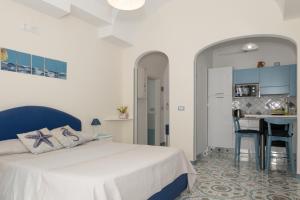a bedroom with a white bed and a kitchen at Libeccio - flat with terrace and sea view, perfect for up to 3 guests in Maiori