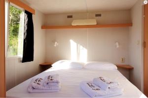 a bedroom with a white bed with towels on it at St.Nicholas Ranch Corfu in Benitses