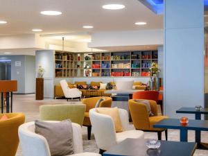 a lobby with chairs and tables and a library at Mercure Hotel Saarbrücken City in Saarbrücken