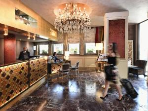 a woman walking past a bar in a hotel lobby at Papadopoli Hotel Venezia - MGallery Collection in Venice