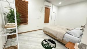 a bedroom with a bed in a white room at Home No 5 in Ratchaburi