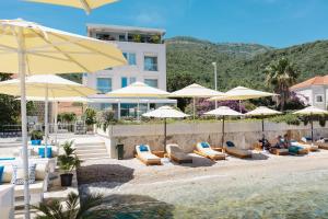 a group of umbrellas and lounge chairs on a beach at Boutique Hotel and Spa Blanc & Bleu - Blanche in Herceg-Novi