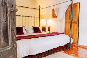 a bedroom with a canopy bed with white sheets and red pillows at Hotel Boutique Morada De Paz in Real de Catorce +13 photos