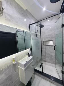 a bathroom with a sink and a glass shower at Maydec Plus Homes & Apartments in Abuja +46 photos