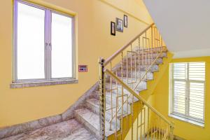 a staircase in a house with yellow walls and two windows at Hotel O White Sapphire in Jādabpur