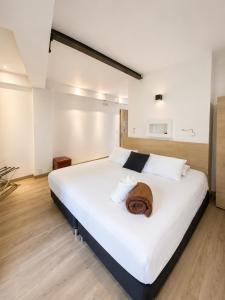 a bedroom with a large white bed with towels on it at Carriqui Garden Hotel in Pereira