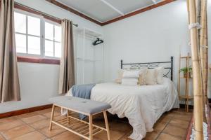 a bedroom with a bed and a chair and a window at Finca del Carmen by Villas Rivero in Santa Maria de Guia de Gran Canaria