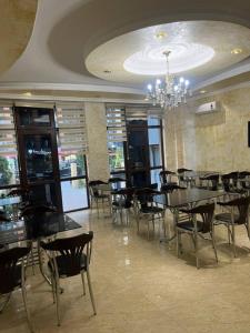 a dining room with tables and chairs and a chandelier at Nelly Hotel in Batumi