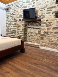 Ein Schlafzimmer mit Steinwand und einem Fernseher auf einem Kamin in der Unterkunft Vila Drasa Guesthouse in Gjirokastër