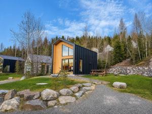 a black and wooden house with a stone wall at Lake Hideaway with BBQ, Fire Pit & Horses in Sainte-Marguerite