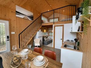 a kitchen and living room with a table and a staircase at Lake Hideaway with BBQ, Fire Pit & Horses in Sainte-Marguerite