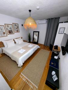 a bedroom with a bed and a television and a chandelier at Garden Relax Bungalow "Deluxe Hotel Rooms, Pool, Parking" in Banja Luka