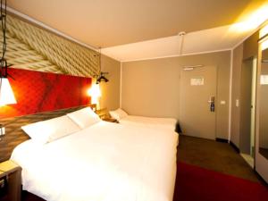 a hotel room with two beds and a red wall at ibis Köln Centrum in Cologne