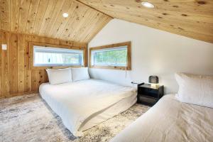 two beds in a room with wooden ceilings at Lake Hideaway with BBQ, Fire Pit & Horses in Sainte-Marguerite