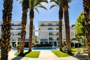 a group of palm trees in front of a building at Barak Royal suites VIP 46 - חמש דקות מהים ומהטיילת in Eilat